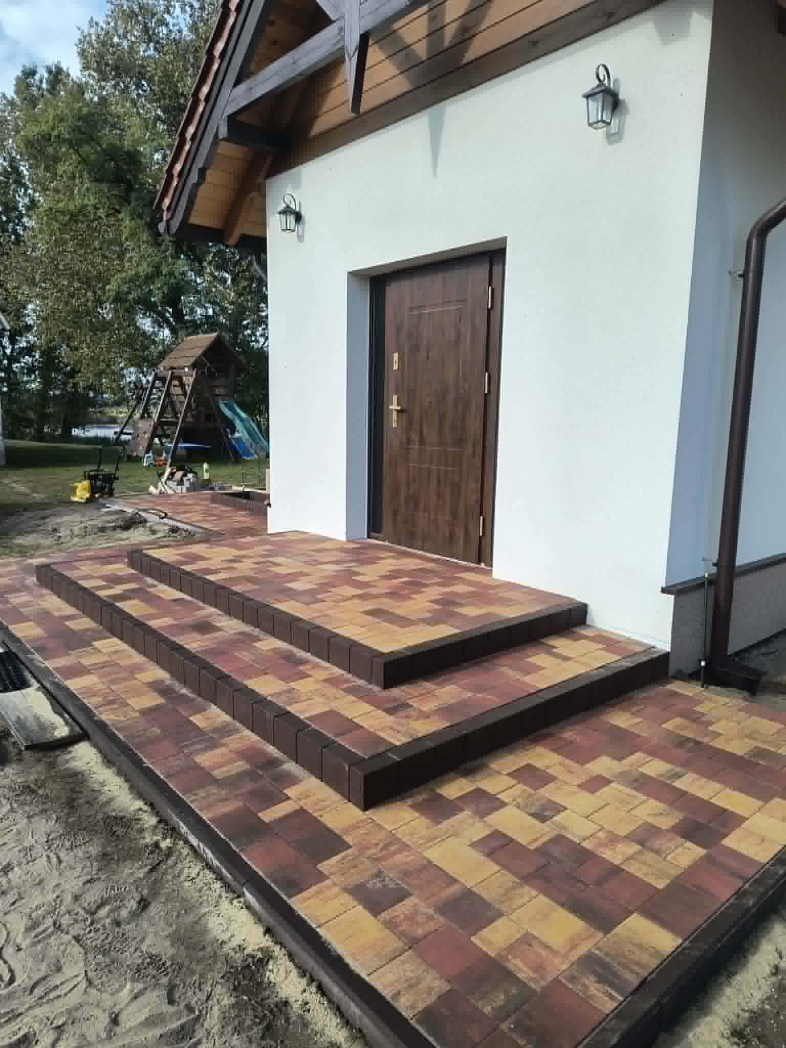 Schody i taras wyłożone kostką brukową przy wejściu do domu